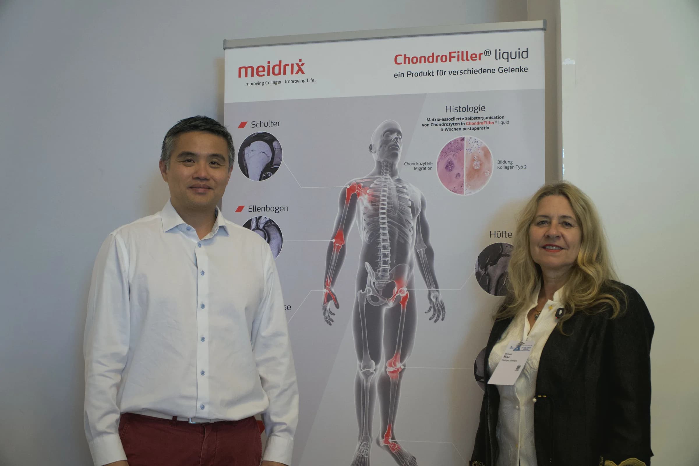 Professor Paul Lee and Dr Michaela Noll standing either side of the meidrix ChondroFiller liquid banner at the 8th ICRS Summit, Porto